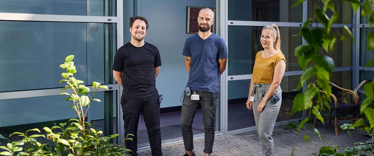3 leden van het psychiatrieteam staan in de tuin van het psychiatriegebouw