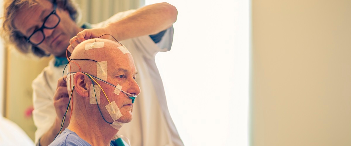 Patiënt krijgt sensoren op zijn hoofd die worden vastgemaakt met plakkers door een sleeptechnologist