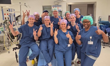 Op de operatiekamer in het ZMC poseert het team met chirurgen en OK medewerkers lachend voor de camera. Ze steken hun duimen trots in de lucht.